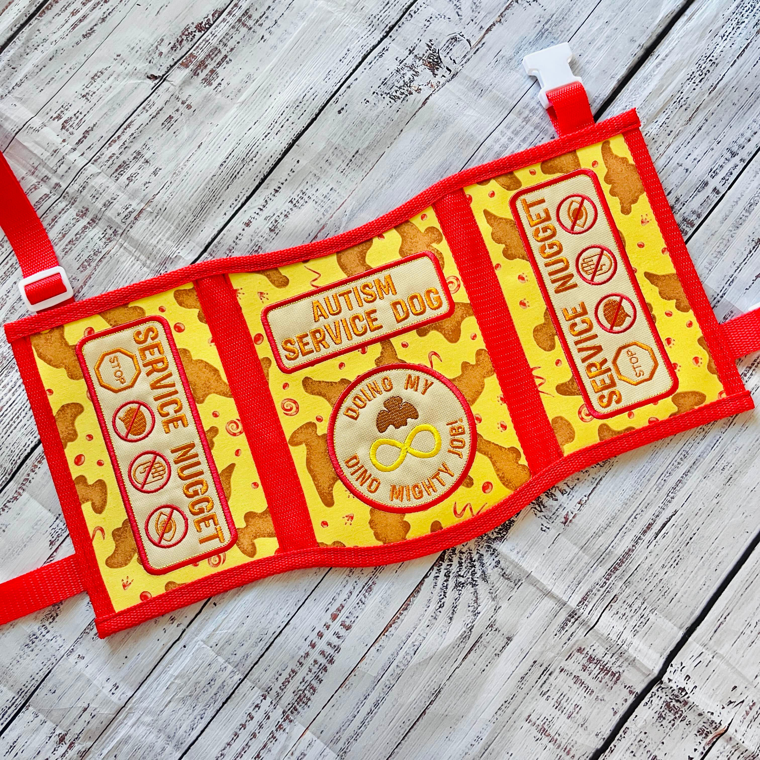 A God of War videogame themed service dog vest. It is gold and dark grey/green with black accents. The panels read: "Medical alert service dog, It is the nature of a thing that matters" "Stop! Do not distract us on our journey. Medical alert service dog"