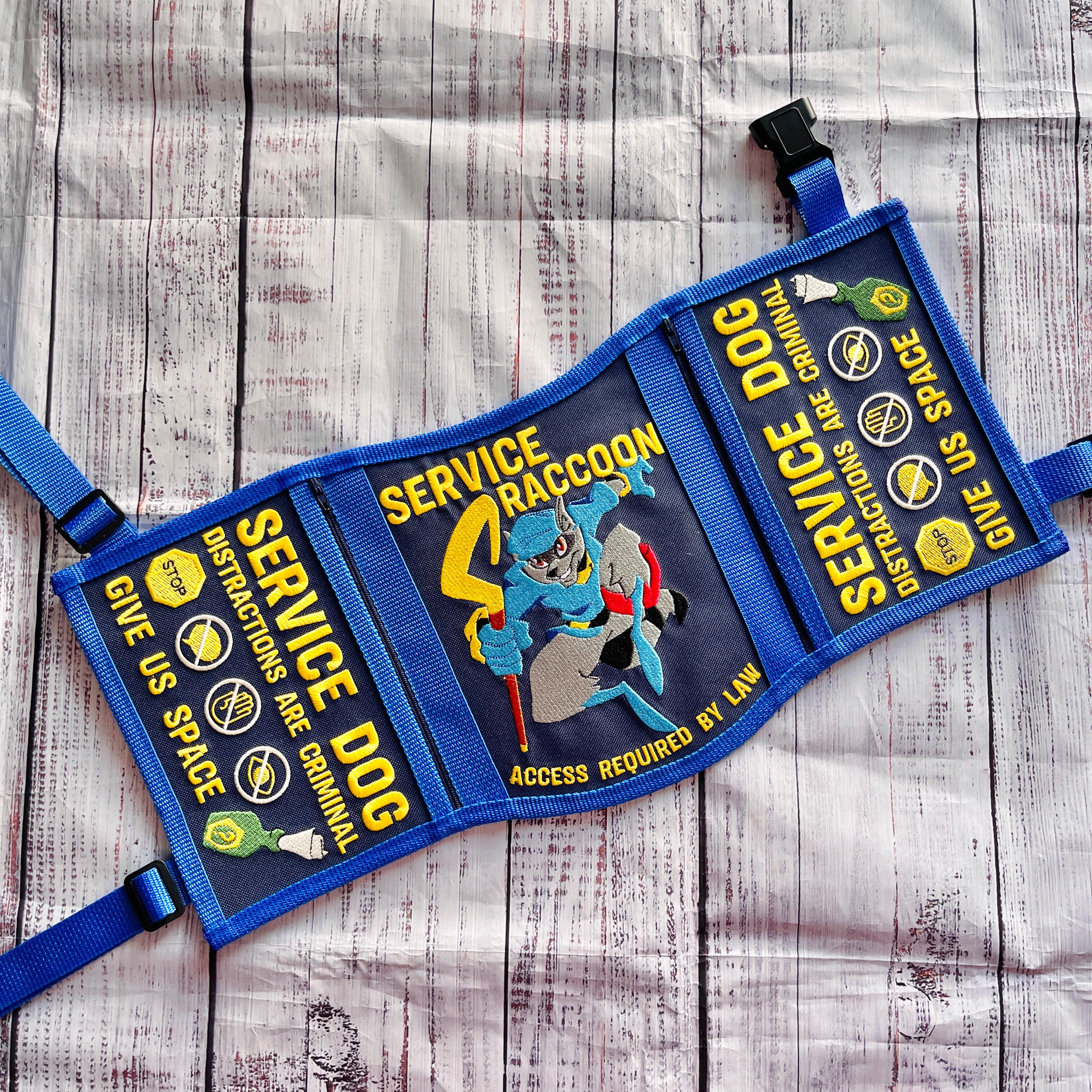 A God of War videogame themed service dog vest. It is gold and dark grey/green with black accents. The panels read: "Medical alert service dog, It is the nature of a thing that matters" "Stop! Do not distract us on our journey. Medical alert service dog"