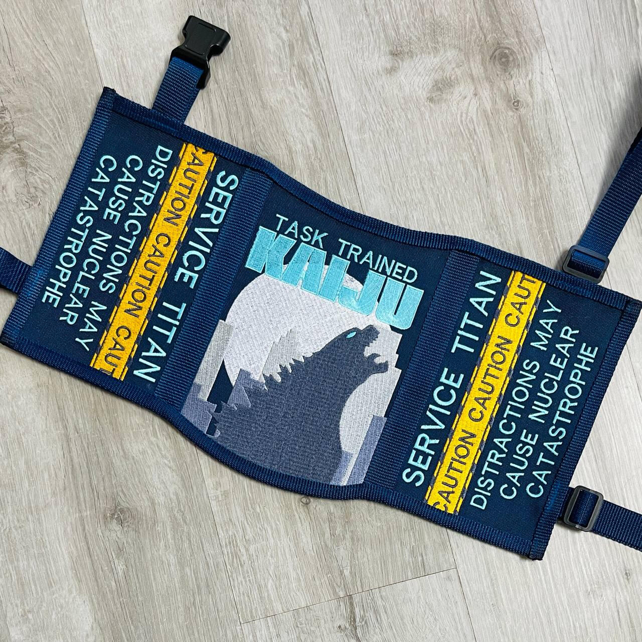 A God of War videogame themed service dog vest. It is gold and dark grey/green with black accents. The panels read: "Medical alert service dog, It is the nature of a thing that matters" "Stop! Do not distract us on our journey. Medical alert service dog"